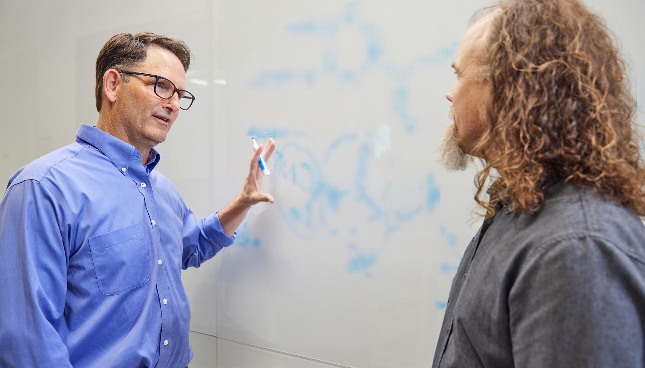 生物生物学家布雷特·克劳福德和丹·温特在白板上讨论一个科学公式